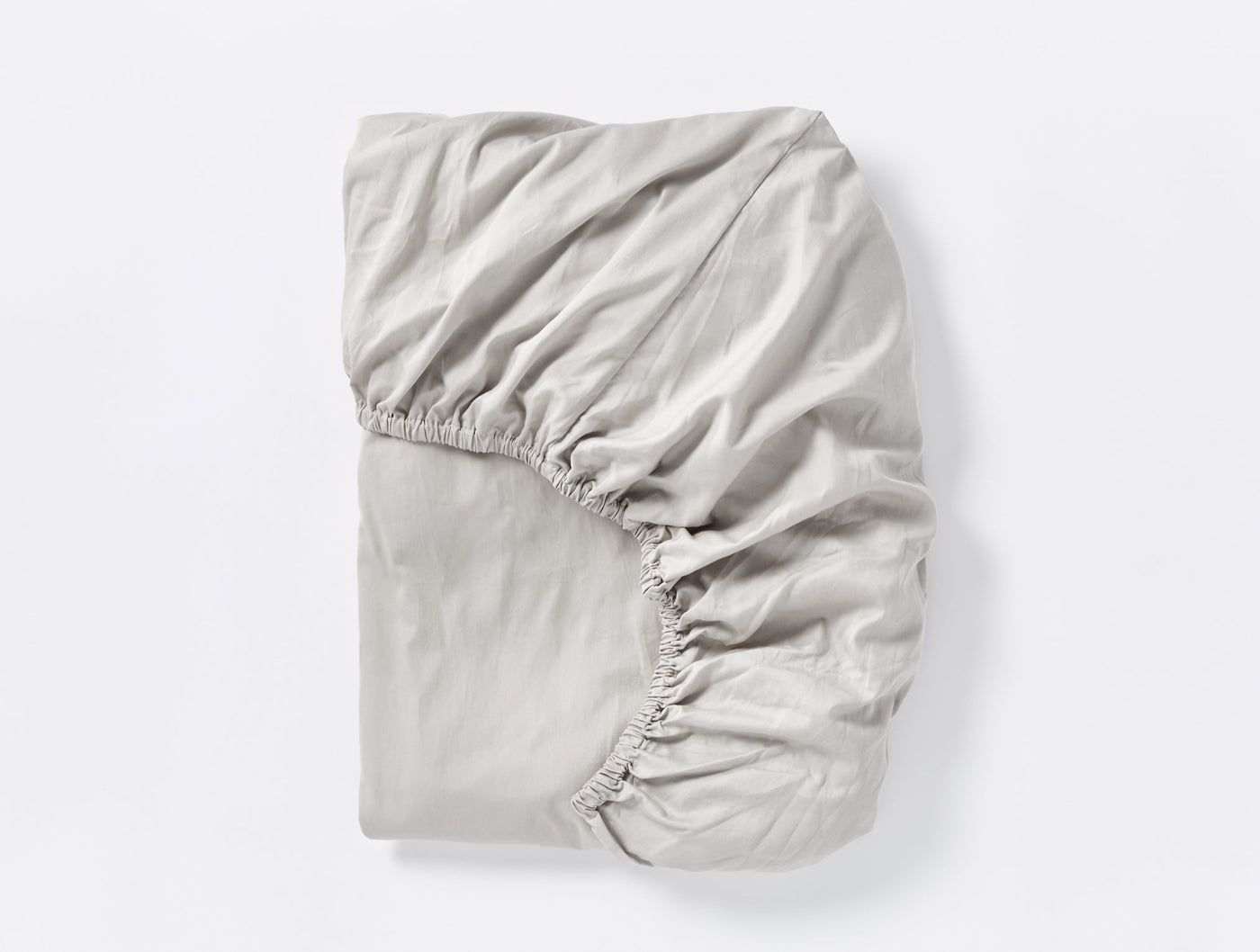 Close-up of Coyuchi Cloud Soft Sateen fitted sheet folded, silver pearl with elasticated corners visible.