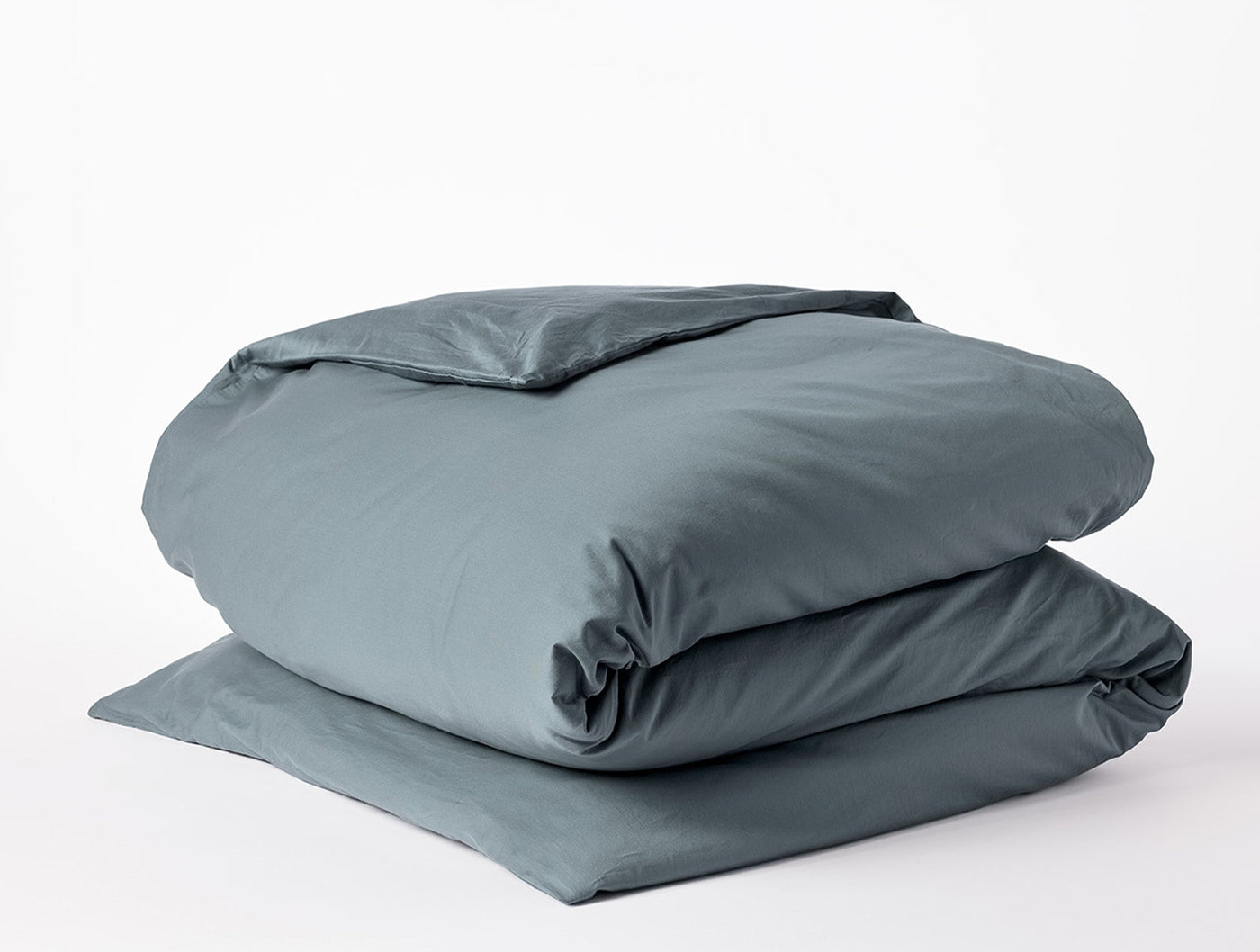 Coyuchi Cloud Soft Sateen duvet cover folded in slate blue, showing smooth sateen finish.