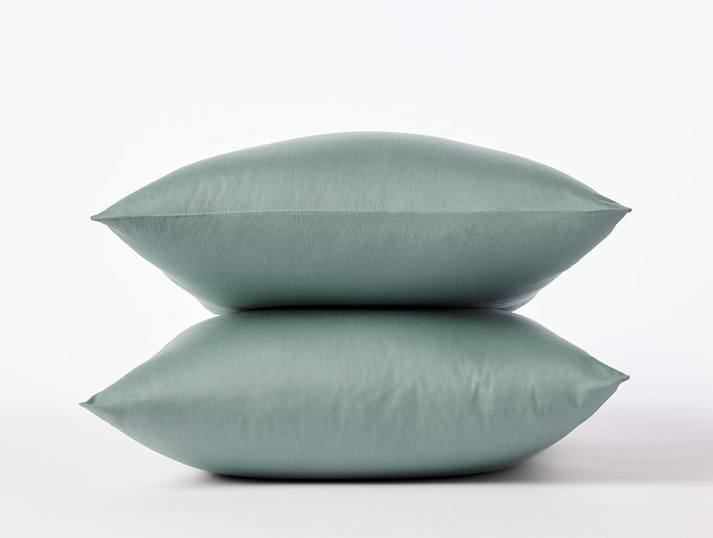 Two stacked sage Coyuchi Cloud Soft Sateen pillowcases against a white background.
