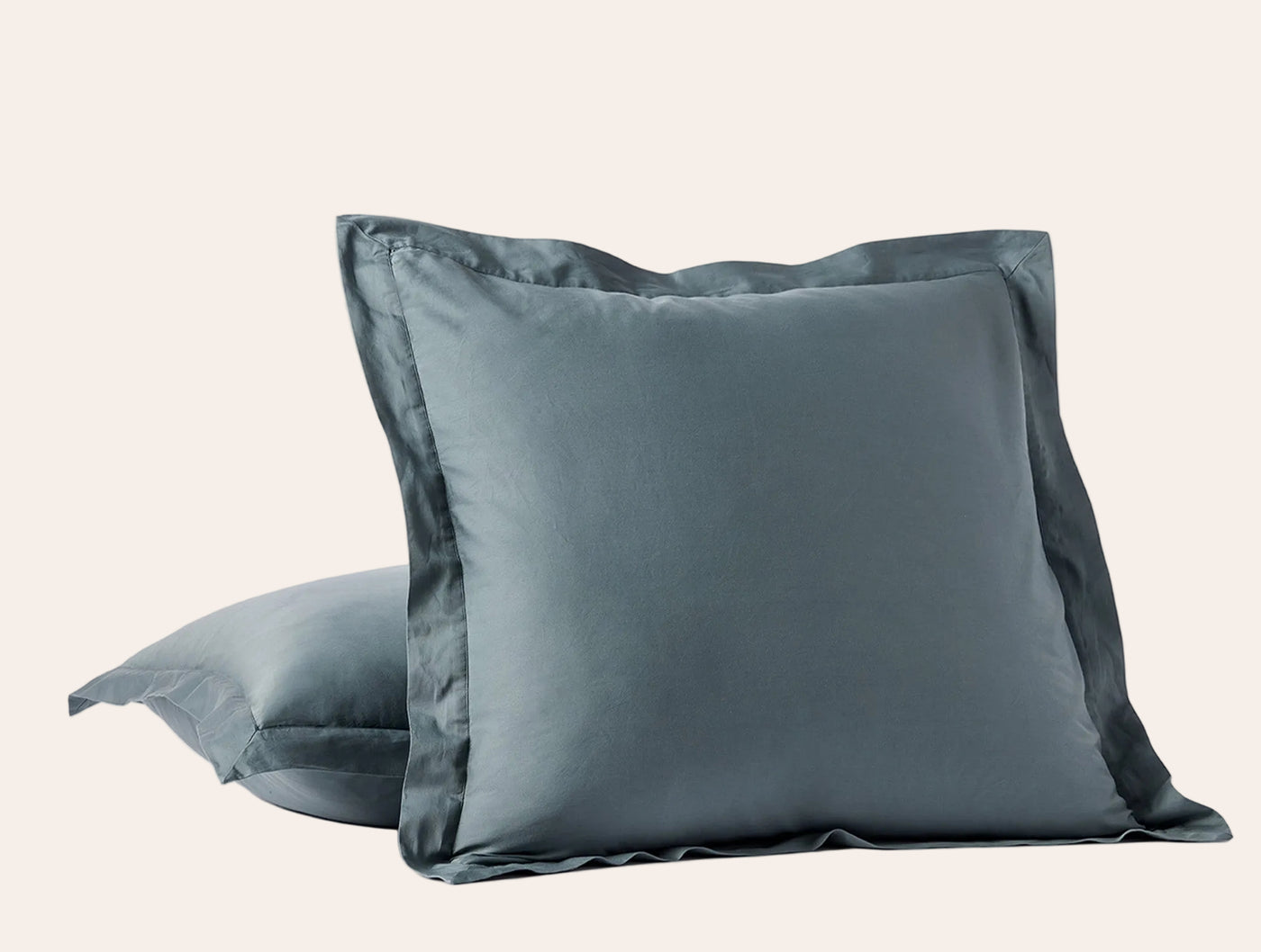 Two slate blue Coyuchi Cloud Soft Sateen shams stacked, front sham showing tailored flange border.