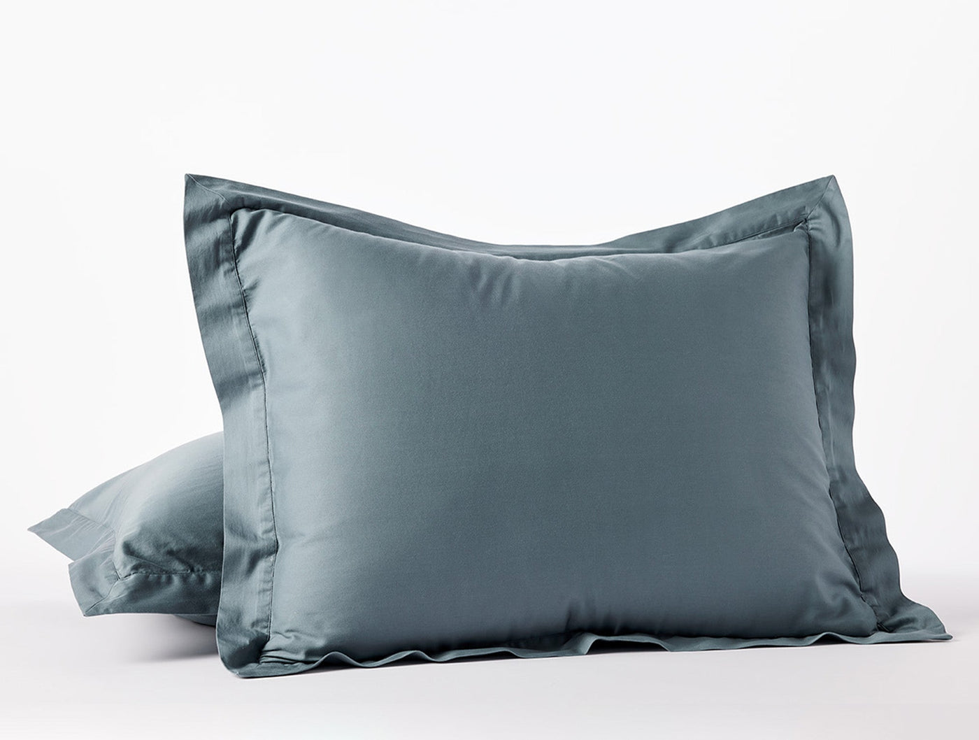 Two slate blue Coyuchi Cloud Soft Sateen pillow shams stacked, showing flanged edge detail.