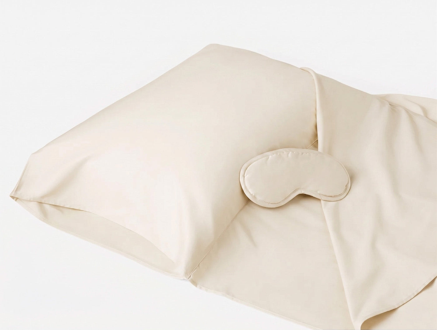 Coyuchi Cloud Soft Sateen travel sack in ivory with matching sleep mask, angled view.