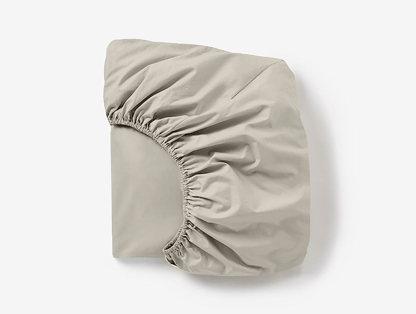 Coyuchi Cloud Soft Sateen fitted sheet folded, showing elasticized corner detail in pebble.