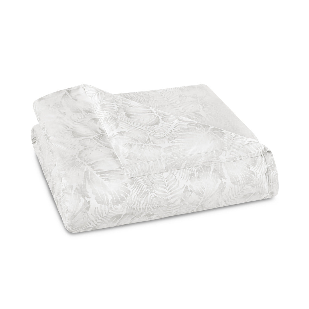 Folded white-on-white duvet cover showing tone-on-tone tropical leaf jacquard pattern.