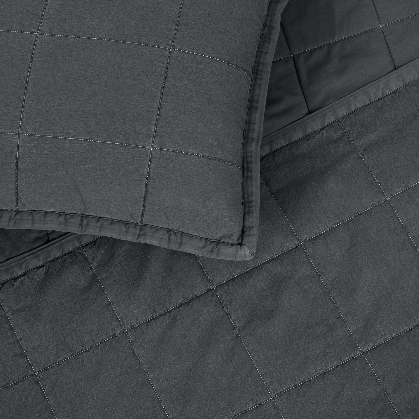 Close-up of charcoal Ann Gish Cotton Canvas coverlet corner with grid quilting and matching sham.