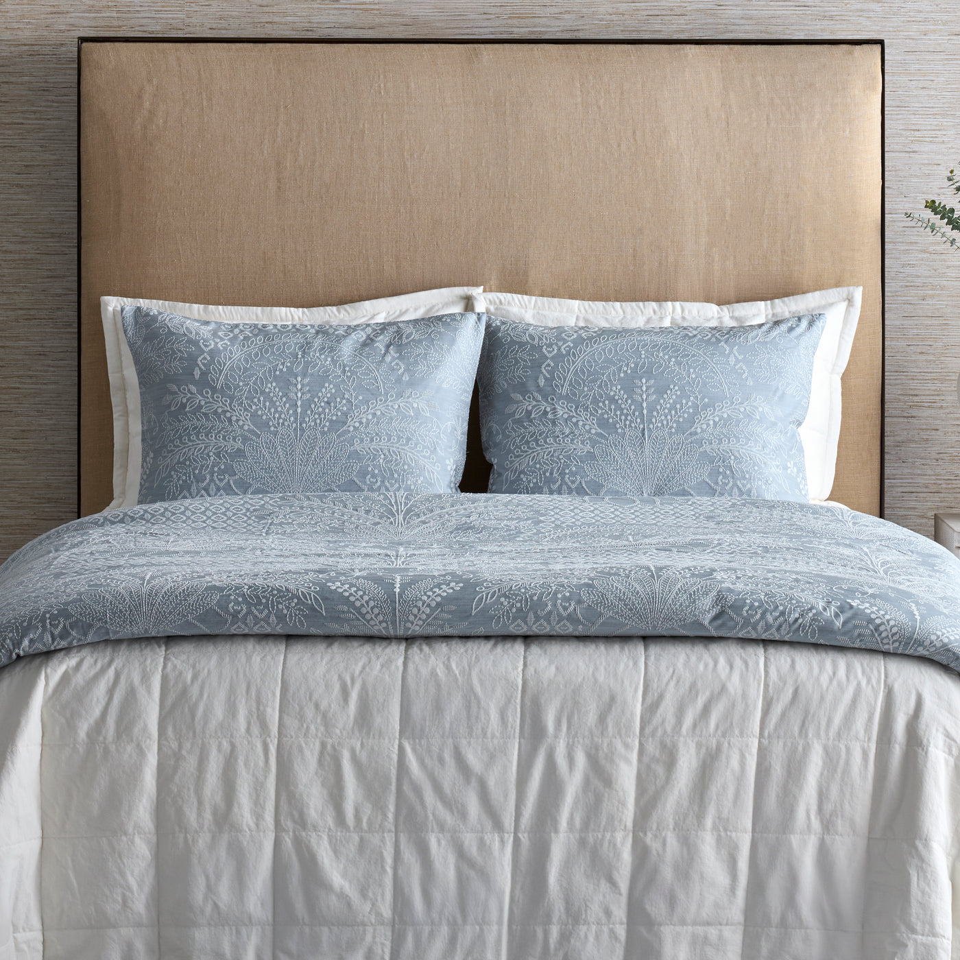 Close-up of Ann Gish Cotton Canvas Coverlet Set in dusty blue with floral jacquard pattern on styled bed.