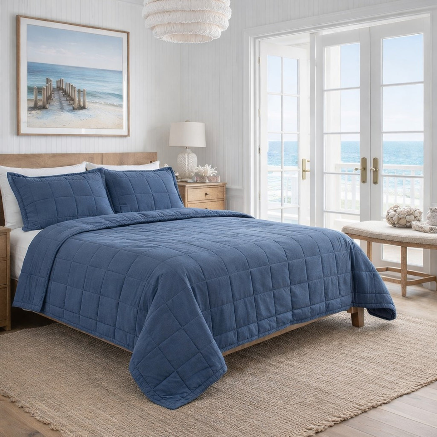 Slate blue quilted cotton coverlet set styled on bed in coastal bedroom setting.