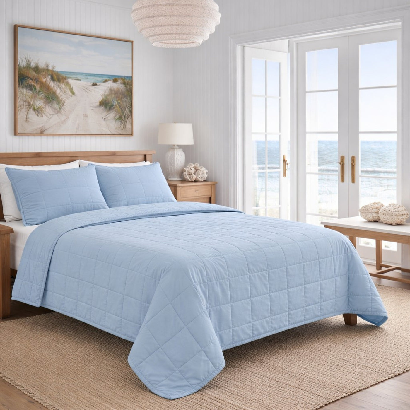Ann Gish Cotton Canvas Coverlet Set in sky blue, grid-quilted, styled on bed in coastal bedroom.