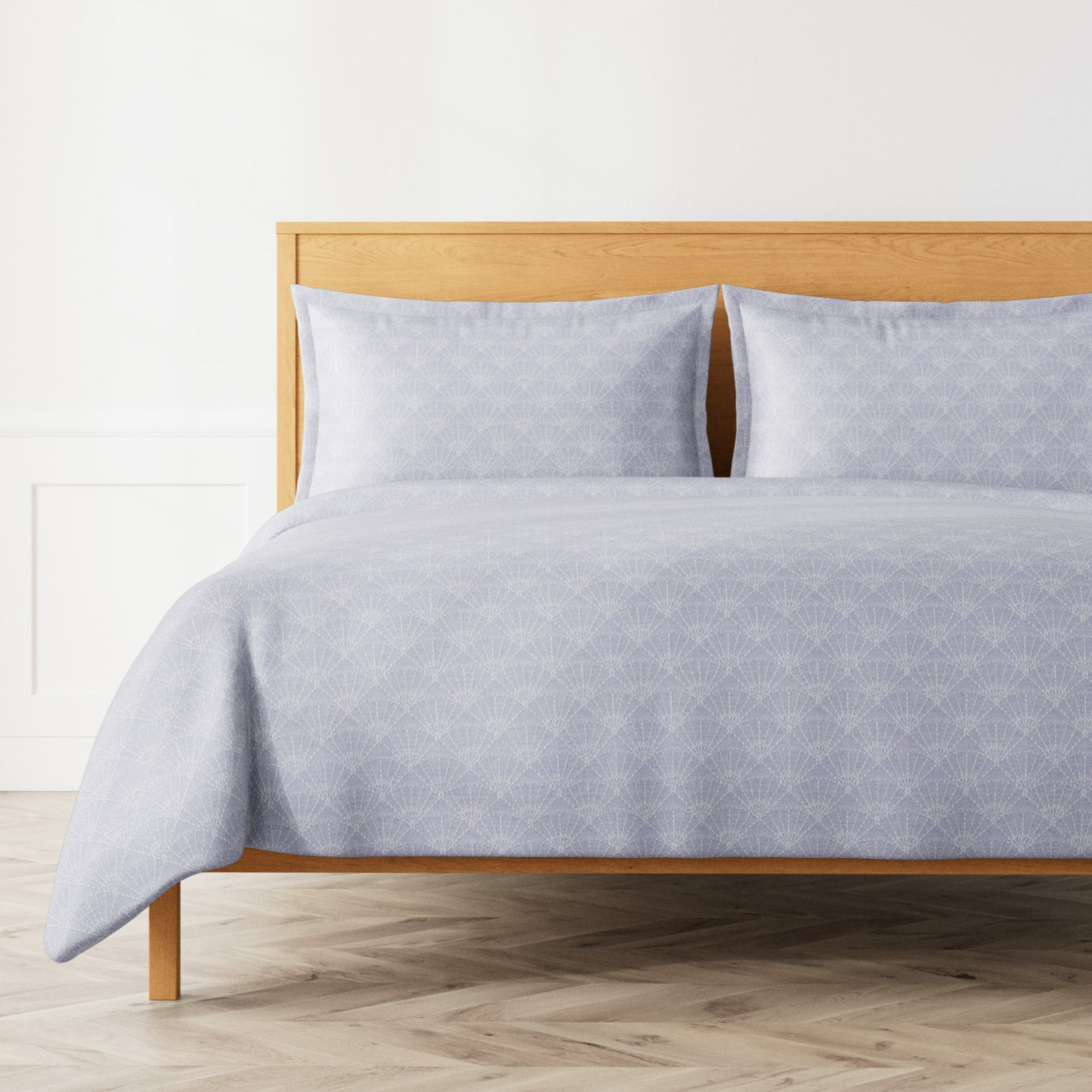 Ann Gish Crest duvet set in lavender with tonal geometric diamond pattern on wood bed.
