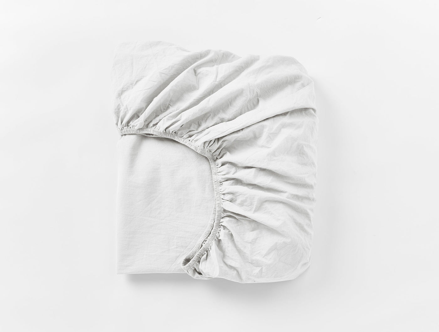 Coyuchi Crinkled Percale fitted sheet in white, folded flat showing elasticated corners.