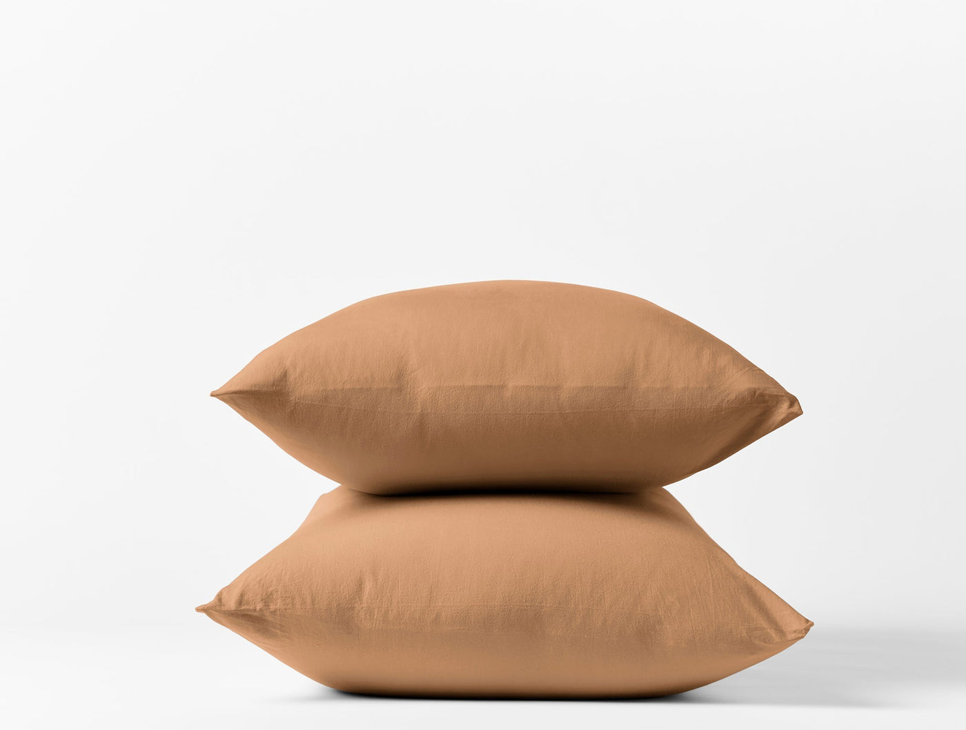 Two caramel Coyuchi Crinkled Percale pillowcases stacked against a white background.