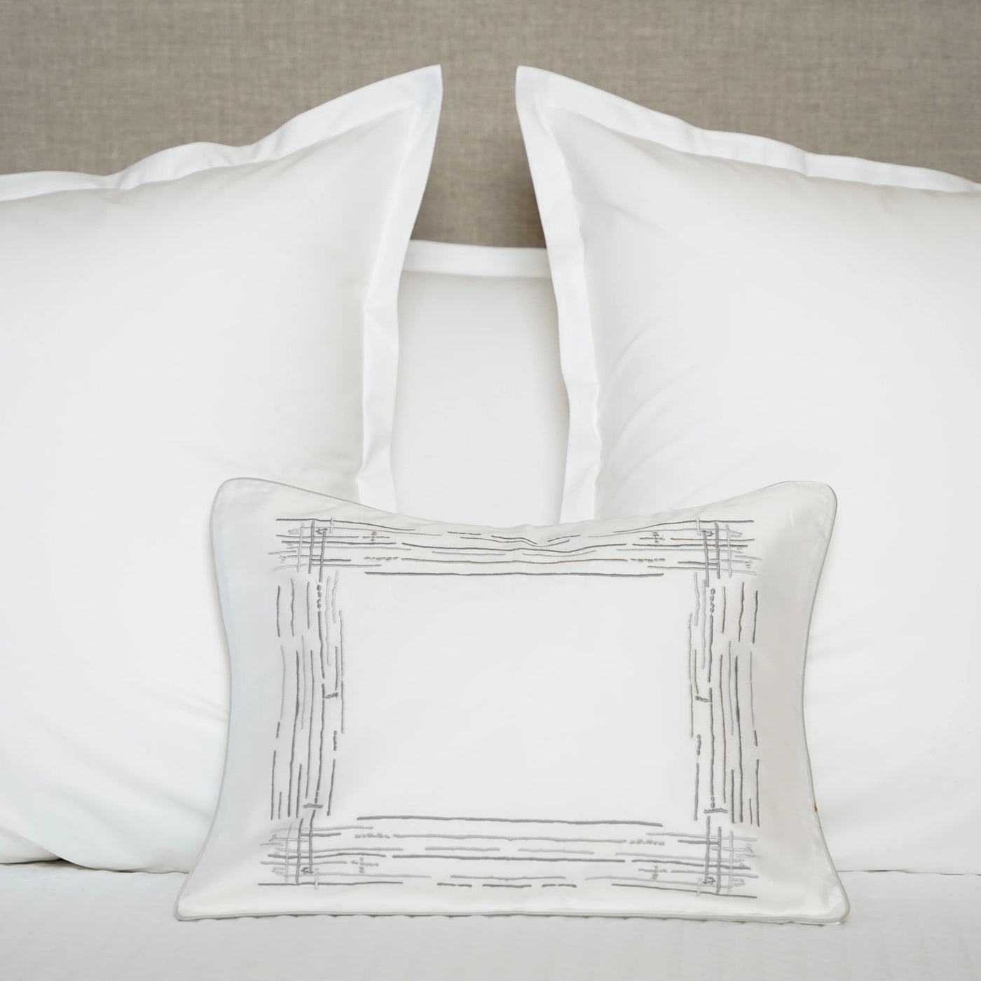 White pillows with a decorative pillow on a neutral background