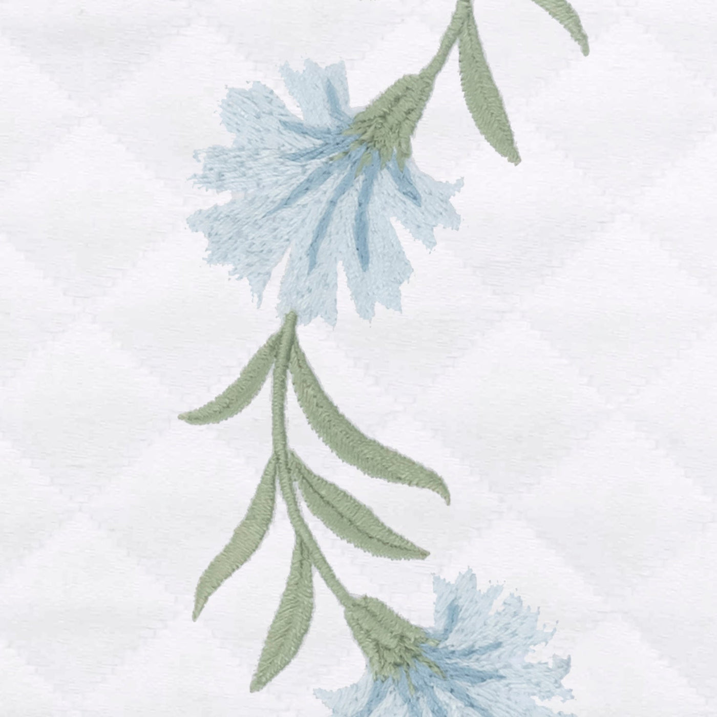 Close-up of sky blue floral embroidery with sage green stems on white diamond matelassé fabric.