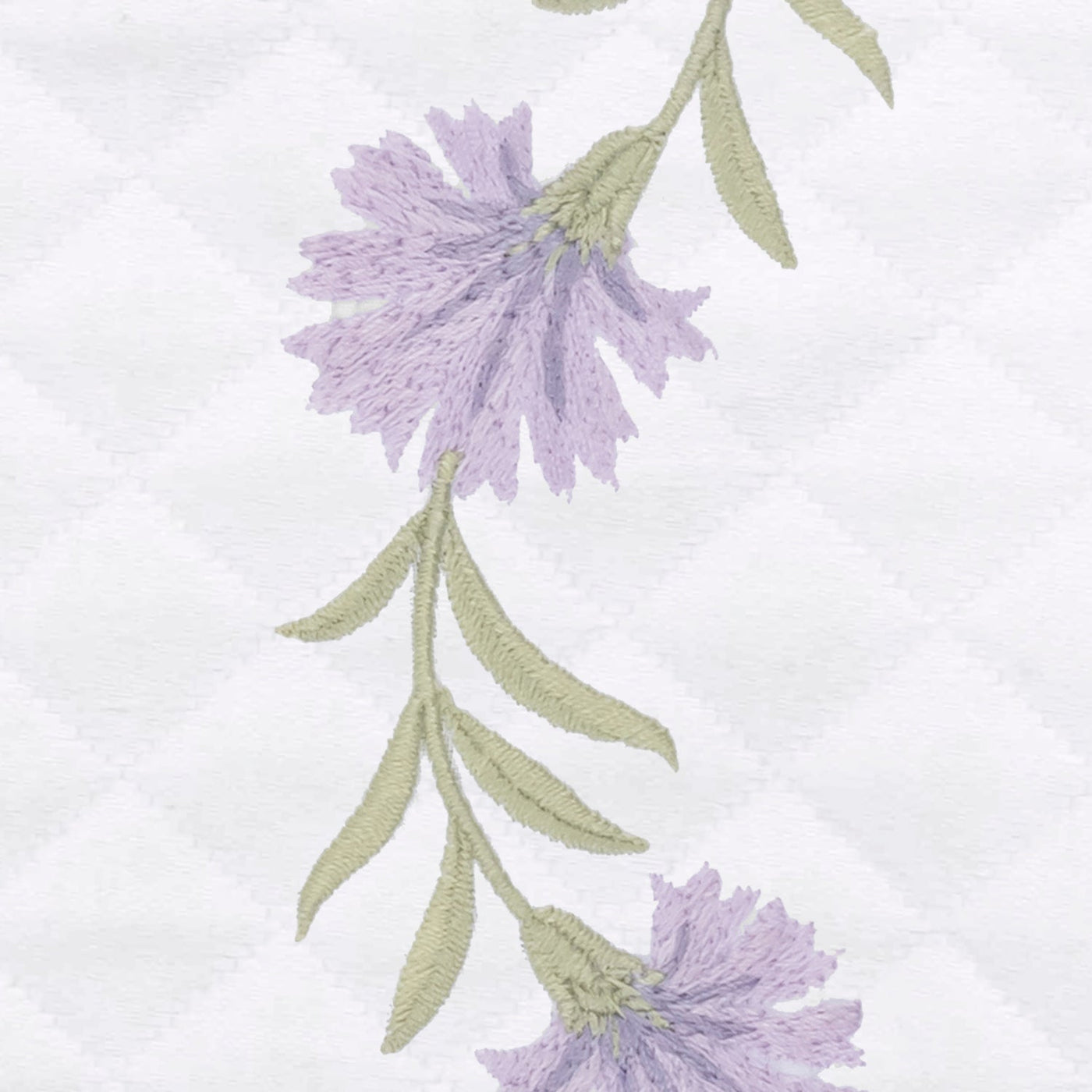 Close-up of lavender floral embroidery with sage stems on white diamond matelassé weave.