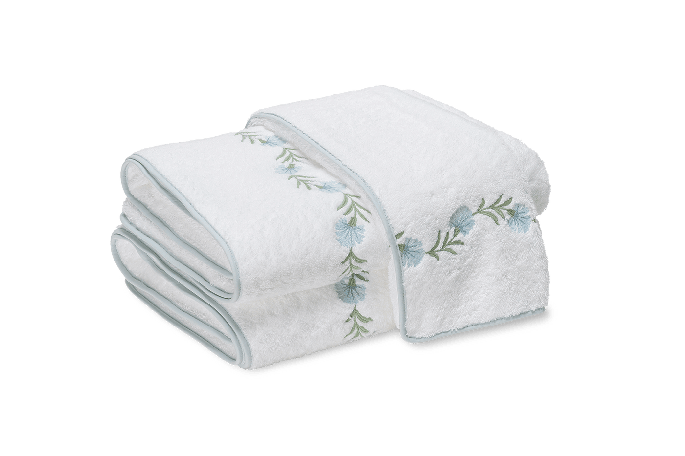 Close-up of folded white bath sheets with sage green floral embroidery and trim.