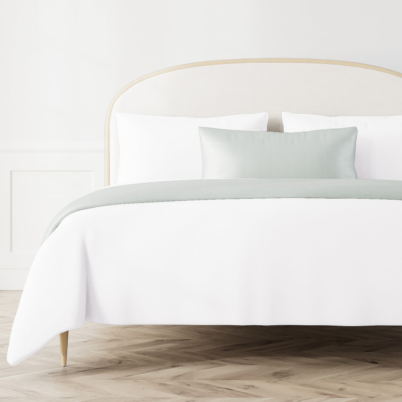 Ann Gish Dapple bed finisher set in sage, styled on a made bed with white bedding.