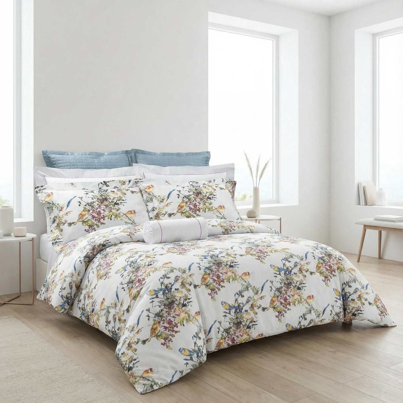 DEA Song Bird duvet set styled on a bed with blue accent pillows in a bright room.