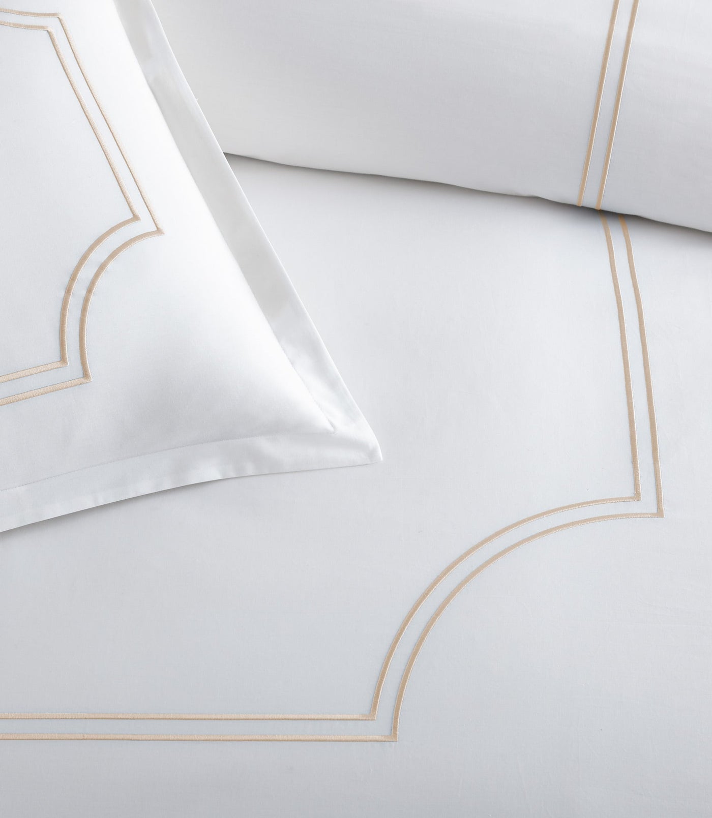 Corner detail of white Peacock Alley Deco duvet cover with champagne double-line embroidery.