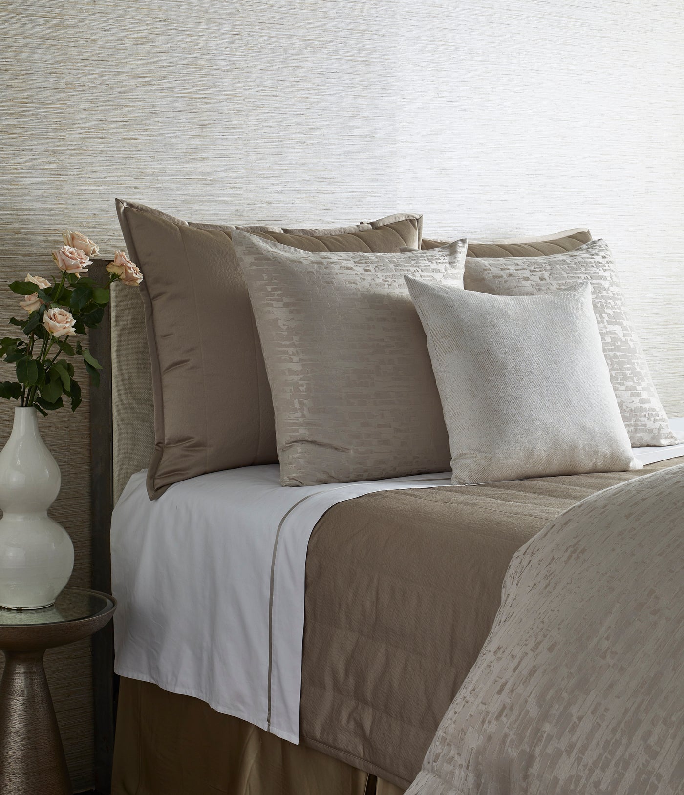 Taupe and ivory bedding ensemble styled on a bed, featuring textured duvet and layered pillows.