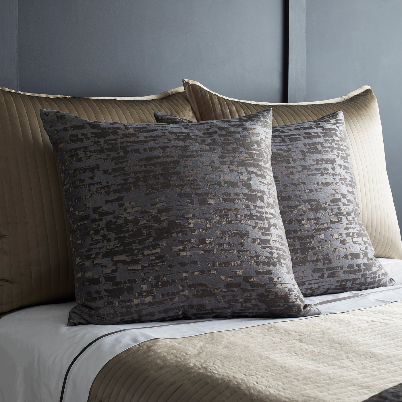 Two Ann Gish Delphi shams in charcoal with textured jacquard pattern, styled on a made bed.