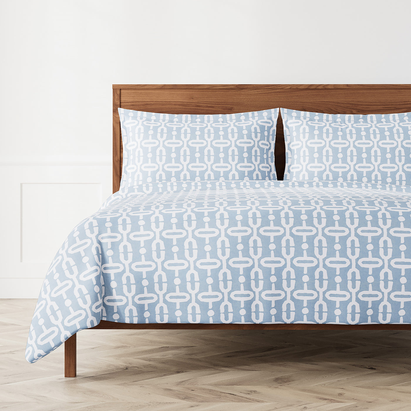 Ann Gish Doorknocker duvet set in sky blue with white geometric chain-link pattern on a styled bed.