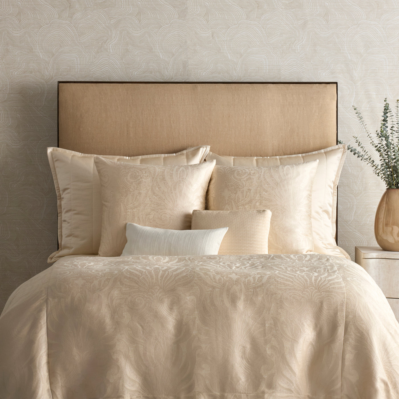 Champagne jacquard floral pillow styled on a layered neutral bedroom bed.
