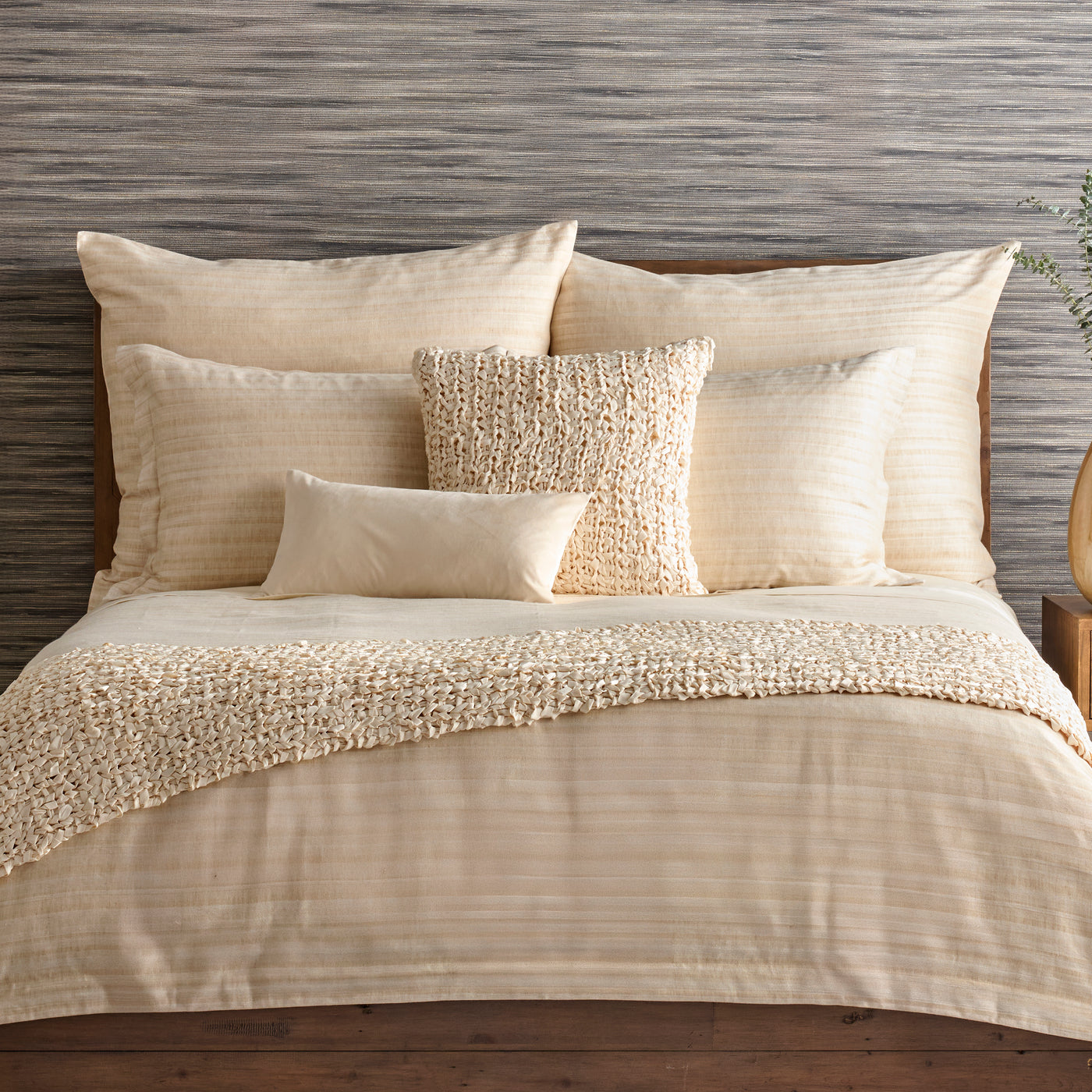 Ivory duvet and pillow collection styled on bed with textured fringe throw and woven accent pillow.