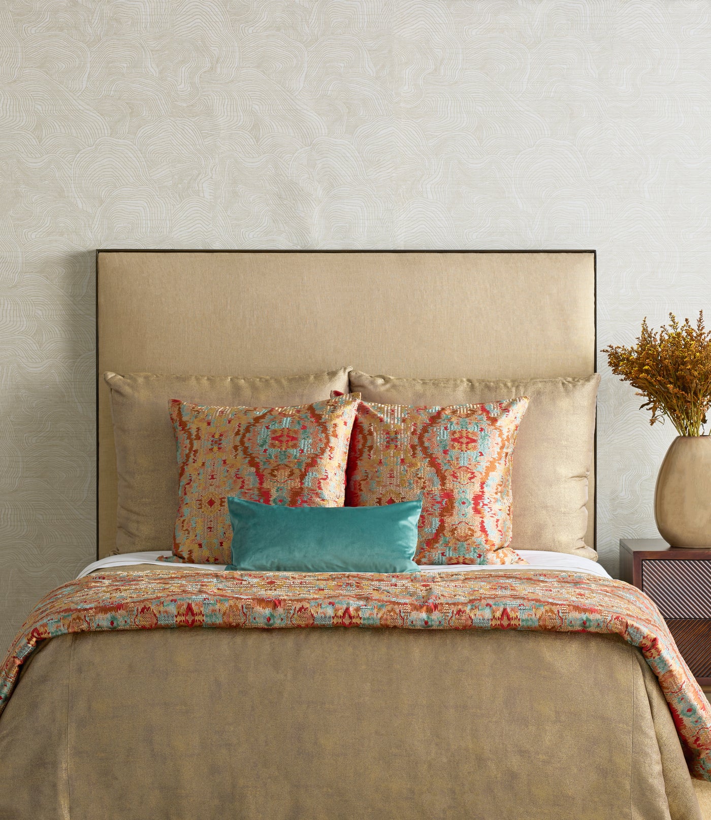 Teal velvet lumbar pillow styled on a bed with ornate coral and turquoise printed bedding.