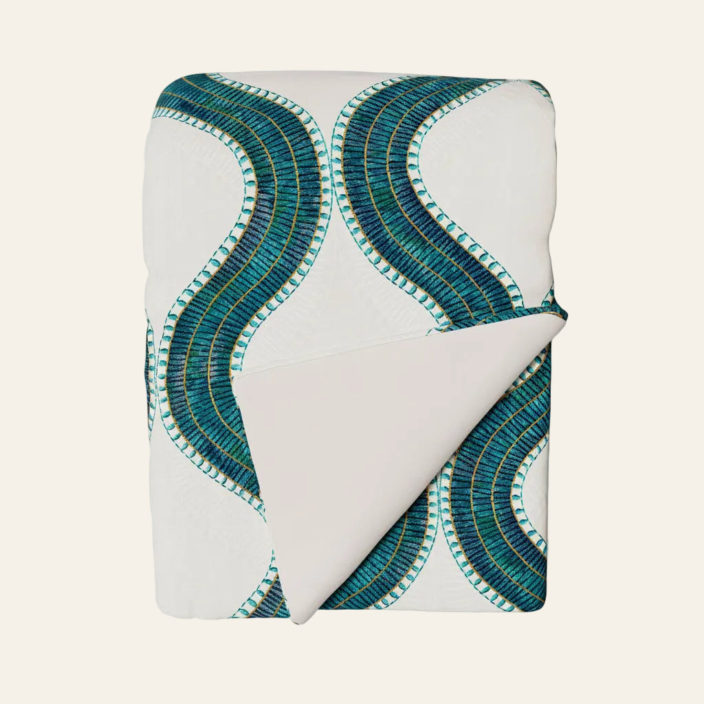 Ann Gish Egyptian Collar throw in white with teal and gold wave embroidery, corner folded back.