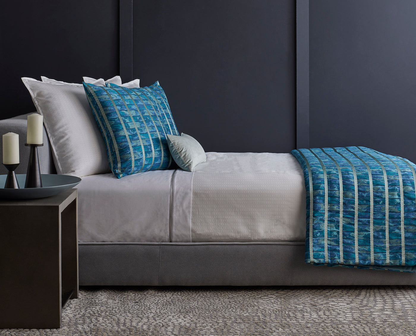 Ann Gish Egyptian Faience throw in teal, draped over gray bedding in a styled bedroom.