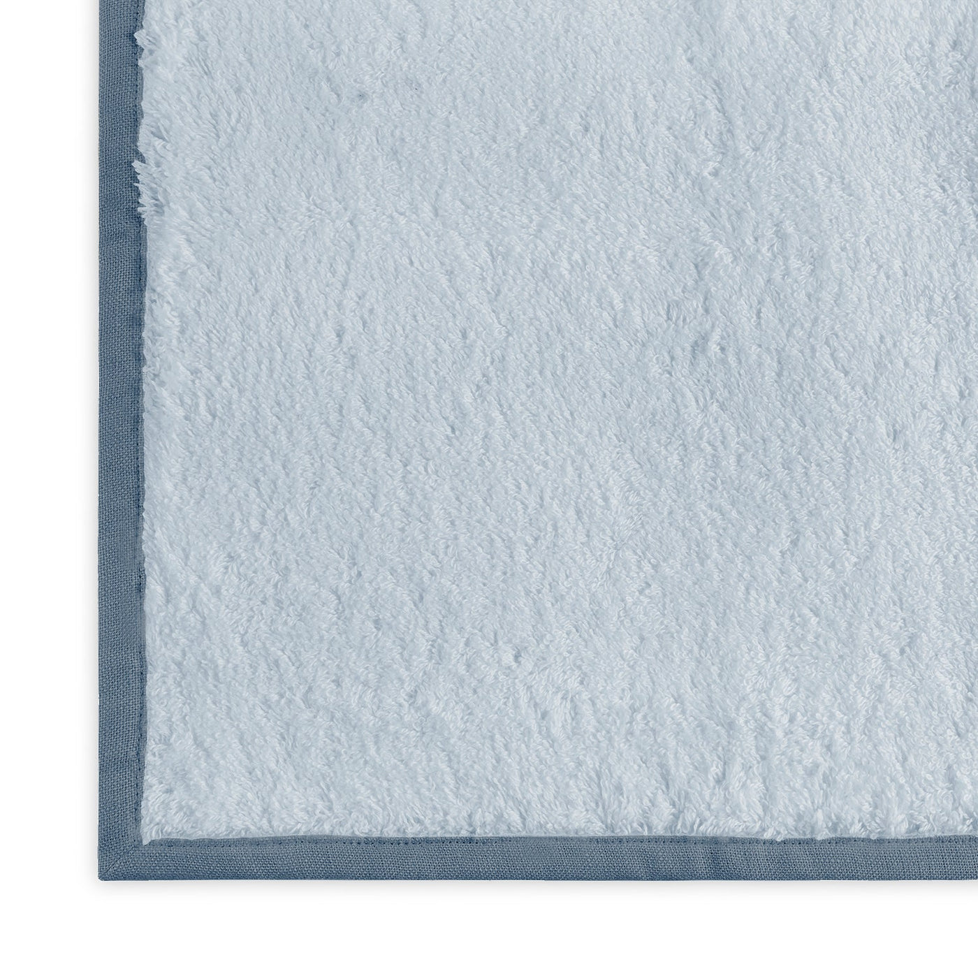 Close-up of powder blue terry tub mat corner with slate blue sateen border trim.