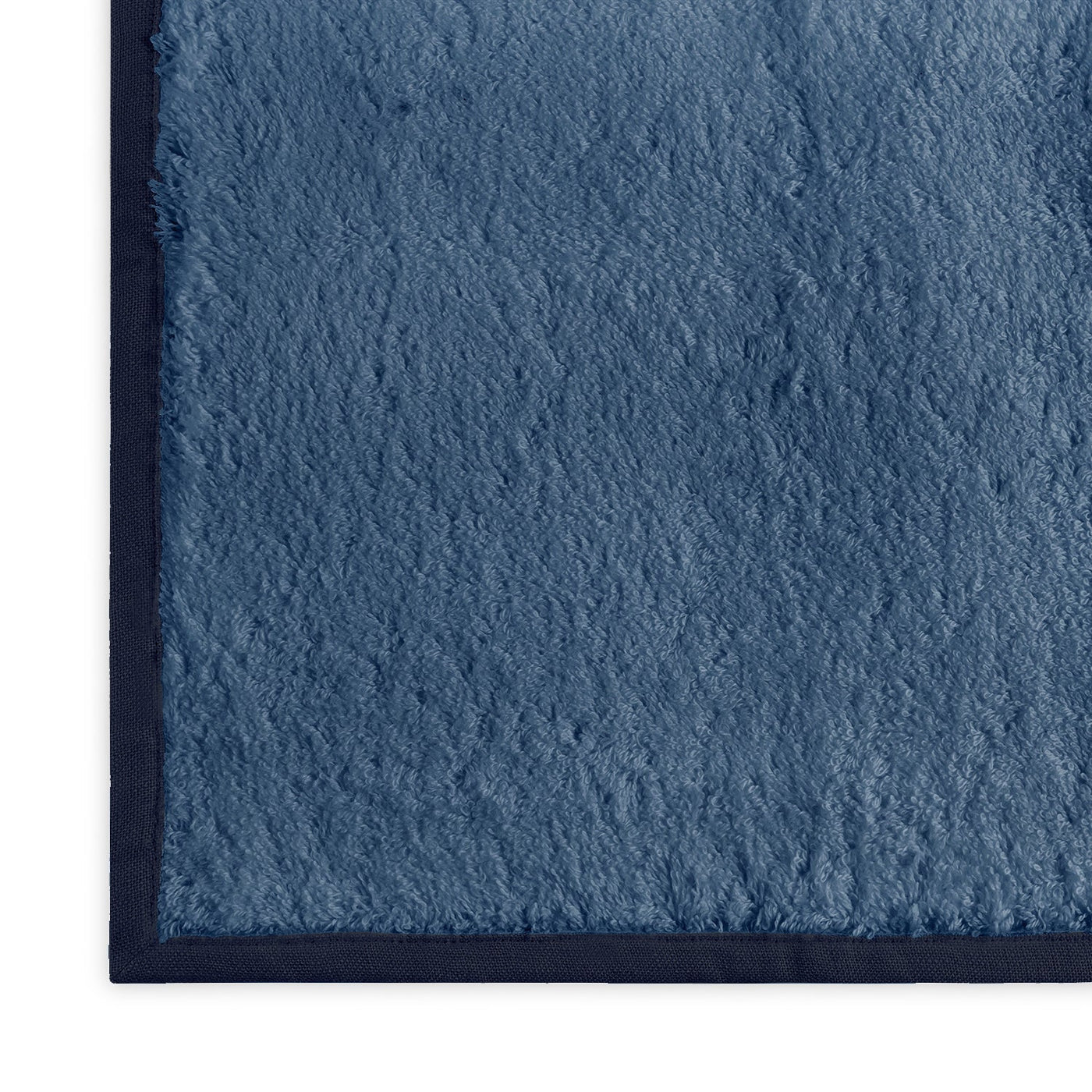 Close-up corner of Matouk Enzo bath sheet in slate blue with navy border trim.
