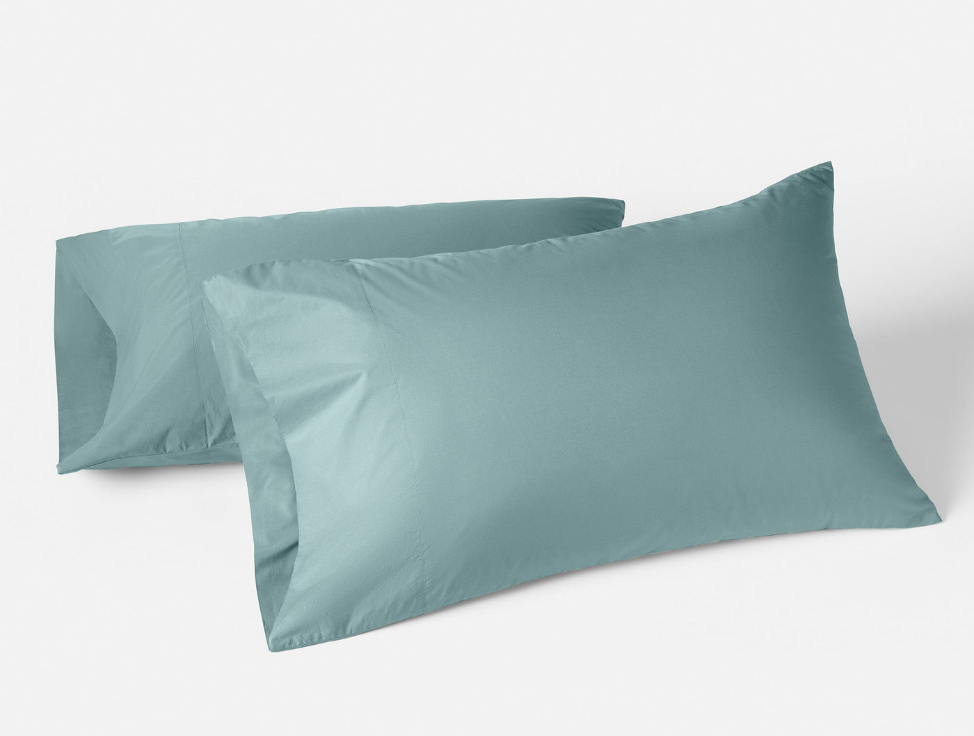 Two Coyuchi Refined Percale pillowcases in muted teal, displayed upright against white background.