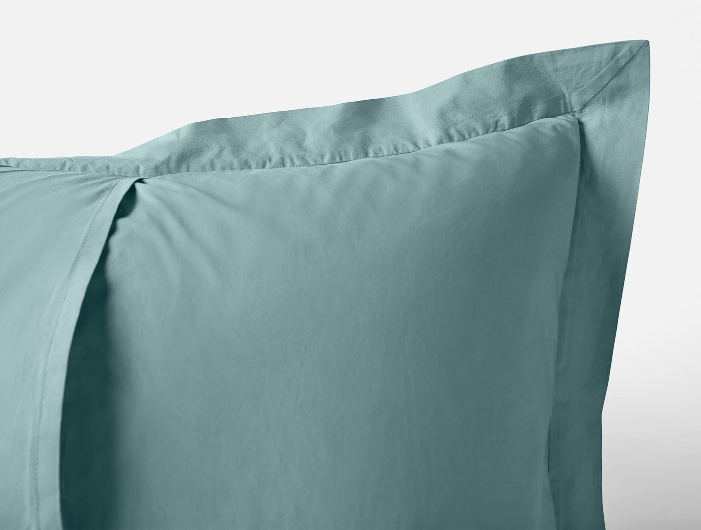 Close-up of Coyuchi Refined Percale sham corner in teal, showing flange detail.