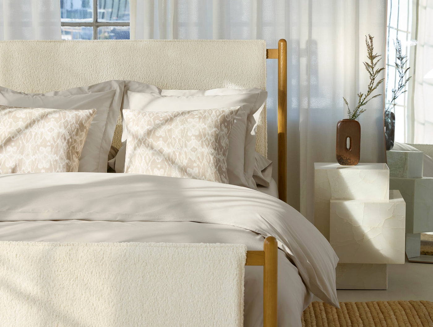 Ivory percale duvet cover styled on bed with patterned shams, natural light, gold bed frame.