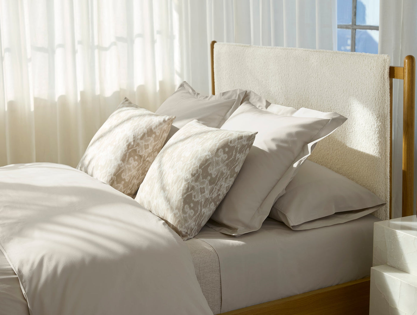 Ivory percale duvet cover styled on a sunlit bed with layered neutral pillows.