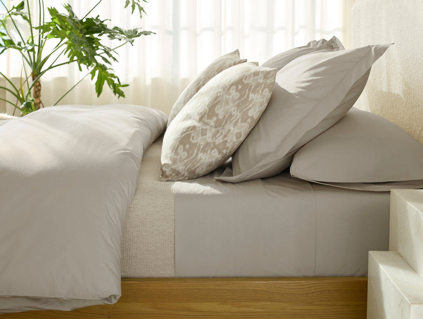 Taupe percale duvet and pillowcases styled on a bed with a floral-print accent pillow.