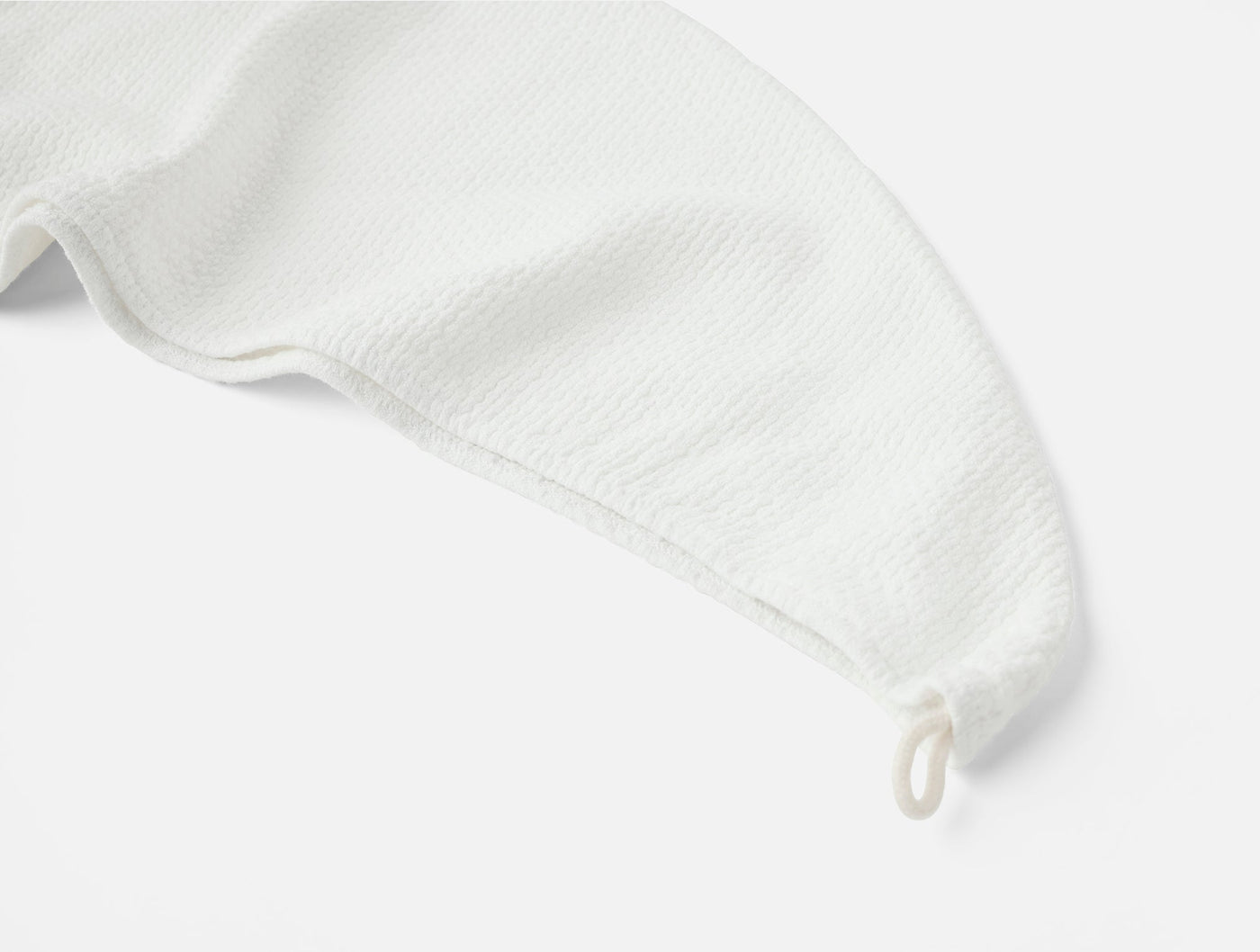 Close-up of white textured hair wrap corner with hanging loop detail.