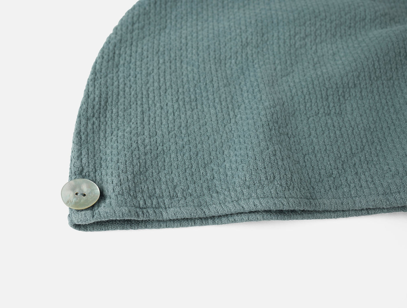 Close-up of seafoam textured cotton hair wrap corner with mother-of-pearl button closure.
