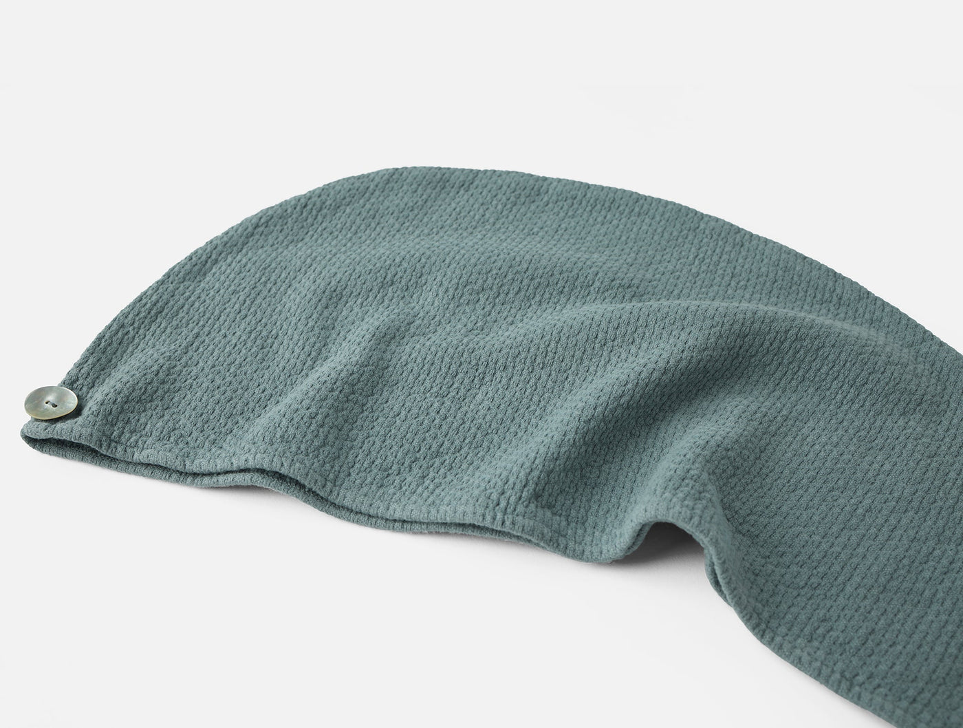 Coyuchi Adriatic hair wrap in sage, close-up showing waffle-knit texture and button closure.