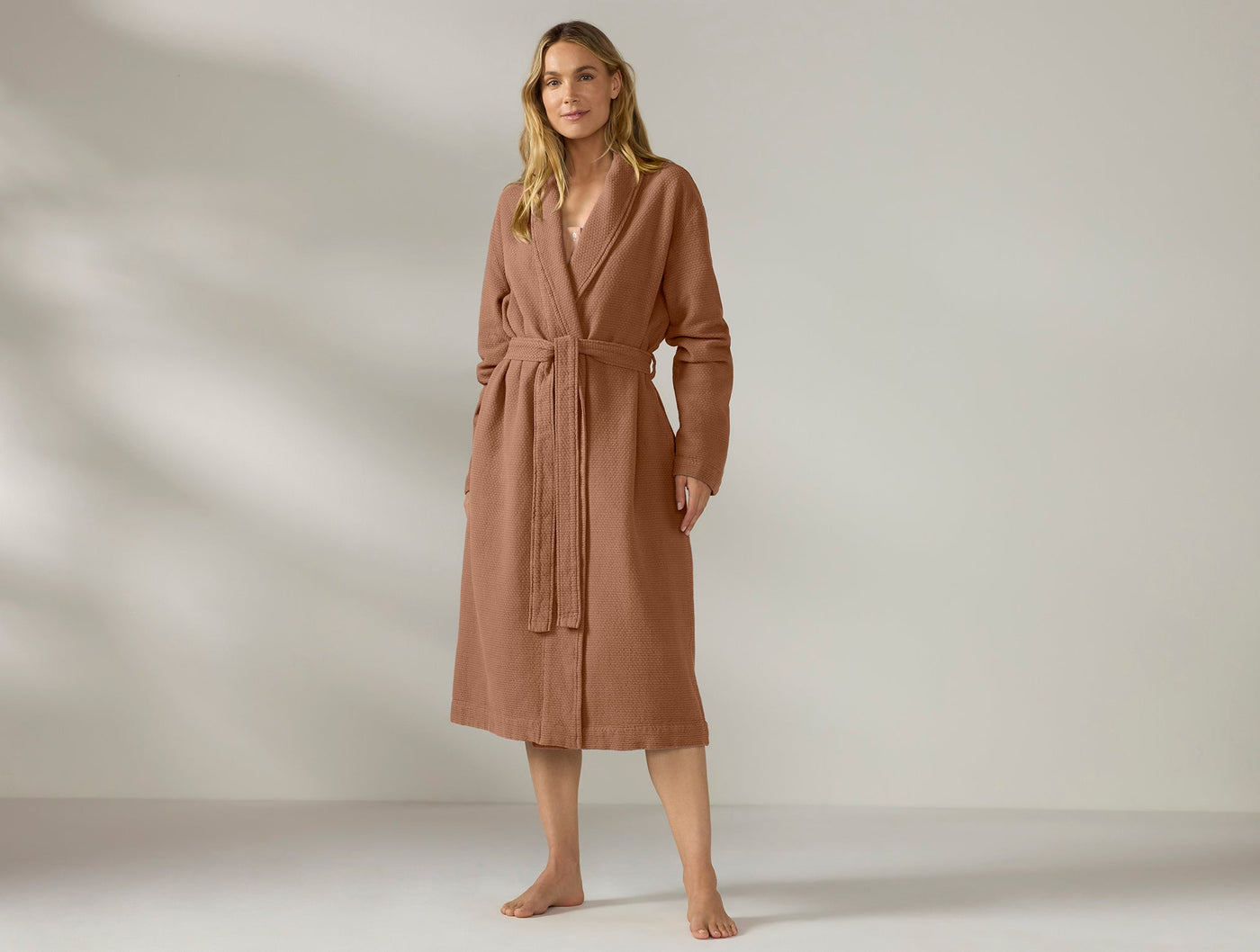 Woman modeling Coyuchi Women's Adriatic Robe in terracotta, full-length front view with tied belt.