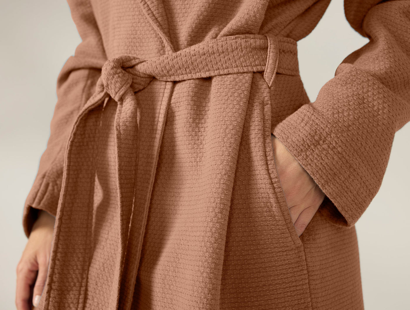 Close-up of Coyuchi Adriatic robe waist tie and pocket detail in terracotta waffle texture.