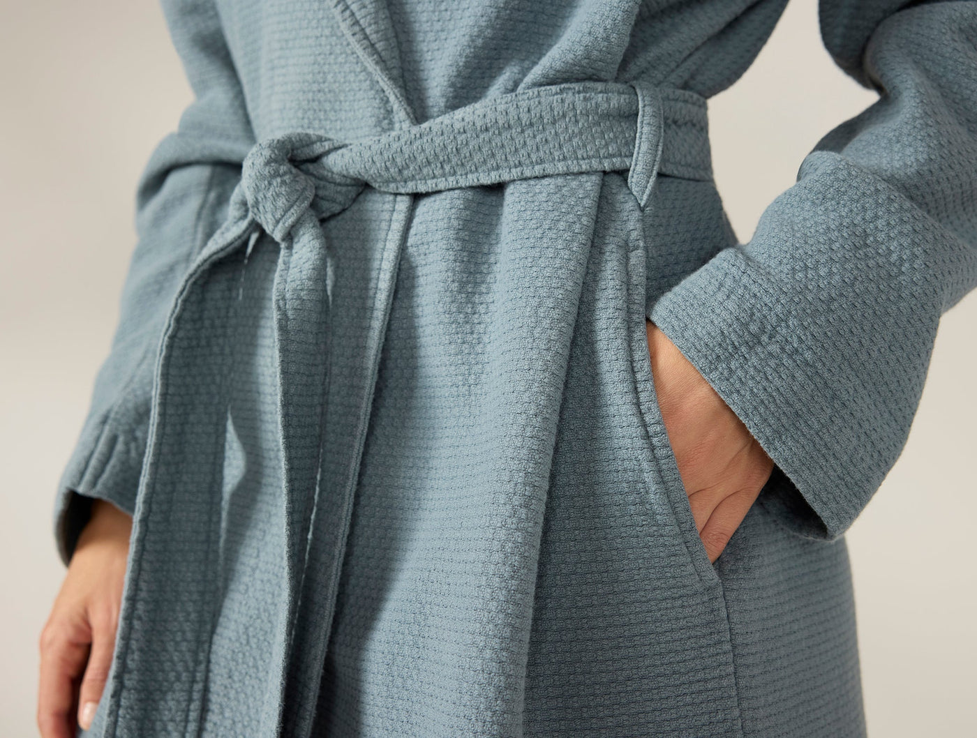 Close-up of Coyuchi Adriatic robe waist tie and pocket detail in slate blue waffle texture.