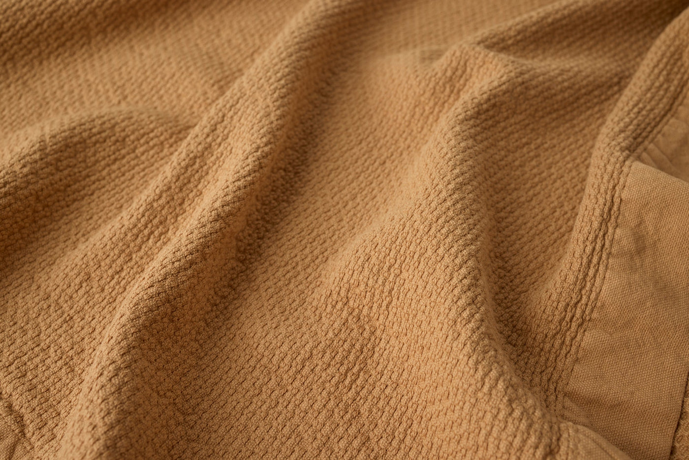 Close-up of caramel waffle-weave texture on a draped Coyuchi Adriatic bath sheet.