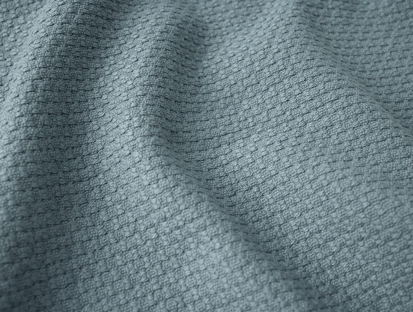 Close-up of Coyuchi Adriatic wash cloth in slate blue with waffle weave texture.