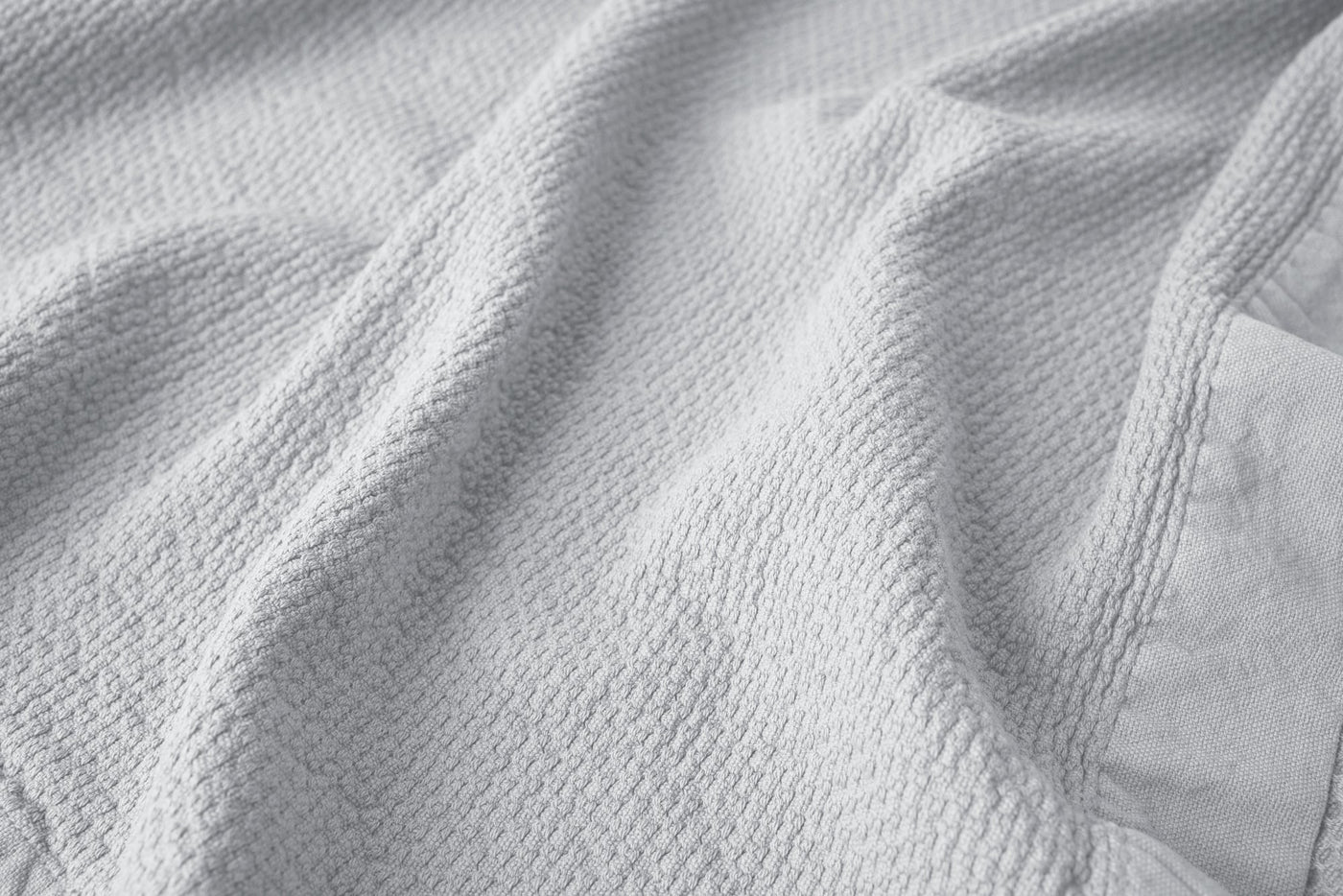Close-up of white waffle-weave texture on Coyuchi Adriatic wash cloth, draped with soft folds.