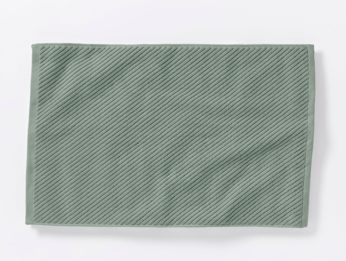 Sage green Coyuchi Air Weight bath rug showing diagonal ribbed twill weave texture, flat lay.