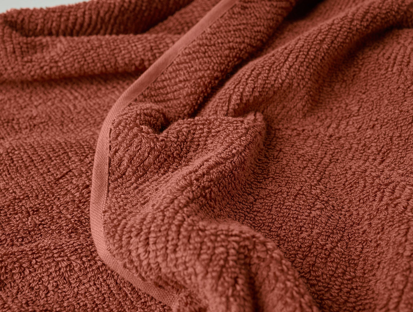 Close-up of Coyuchi Air Weight guest towel in terracotta, showing looped waffle-weave texture.