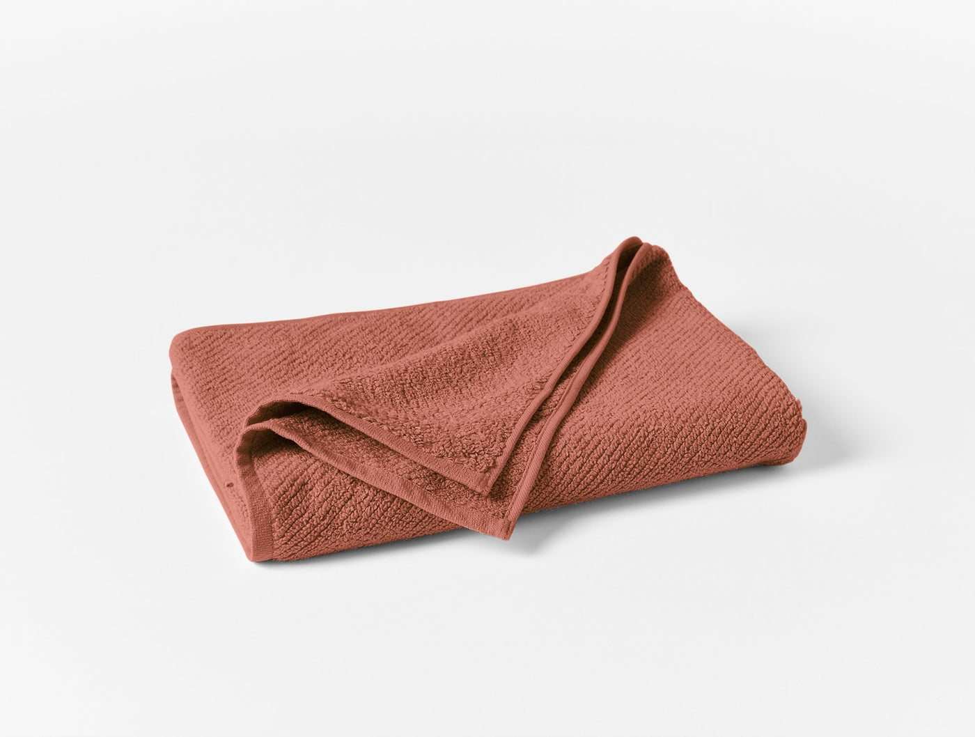Coyuchi Air Weight bath towel folded flat, terracotta textured cotton weave.