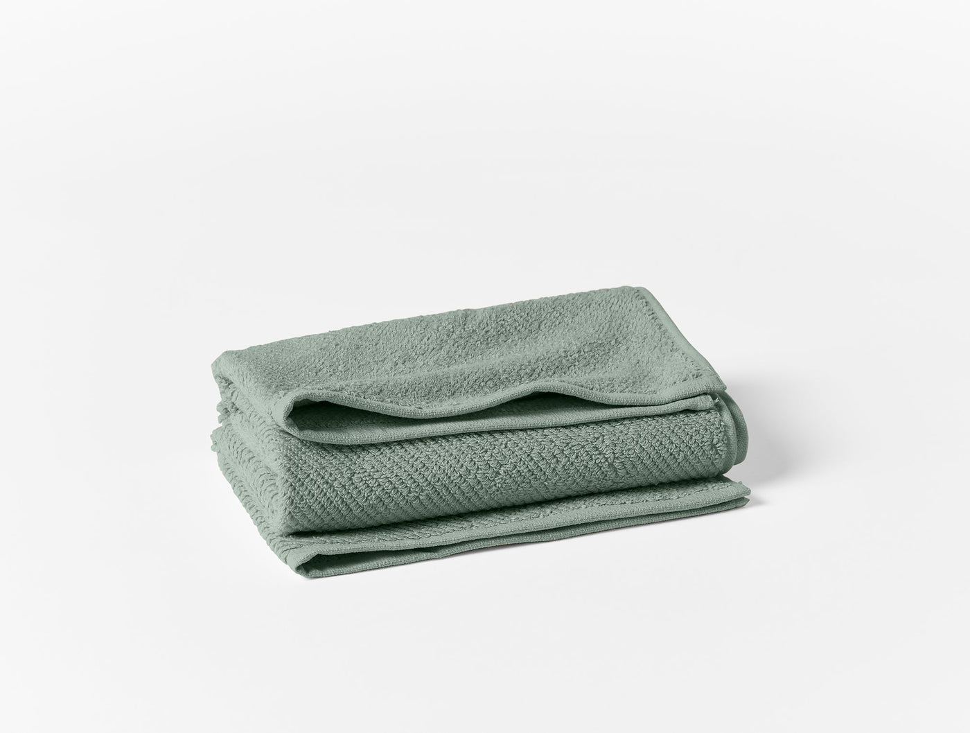 Folded sage green Coyuchi Air Weight oversized hand towel showing textured weave detail.